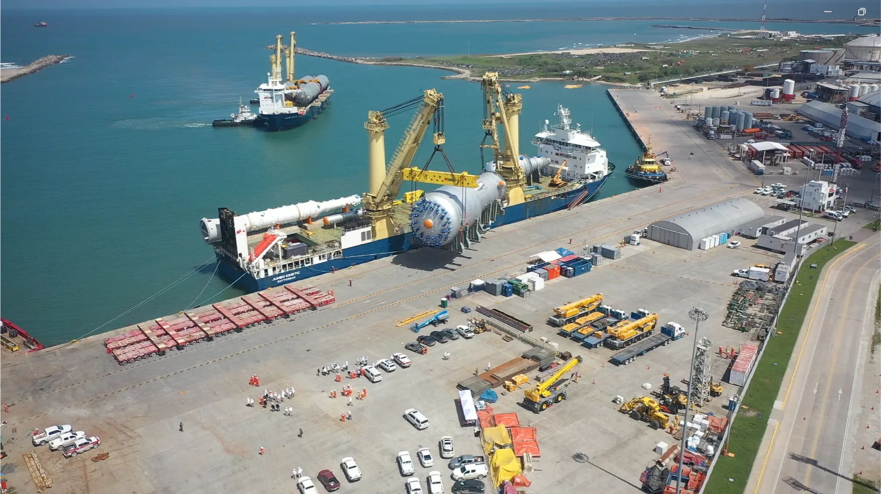 Aerial view of a busy port with cargo ships and cranes.