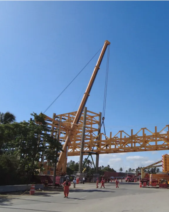 Construction workers operating a crane lifting a steel structure.