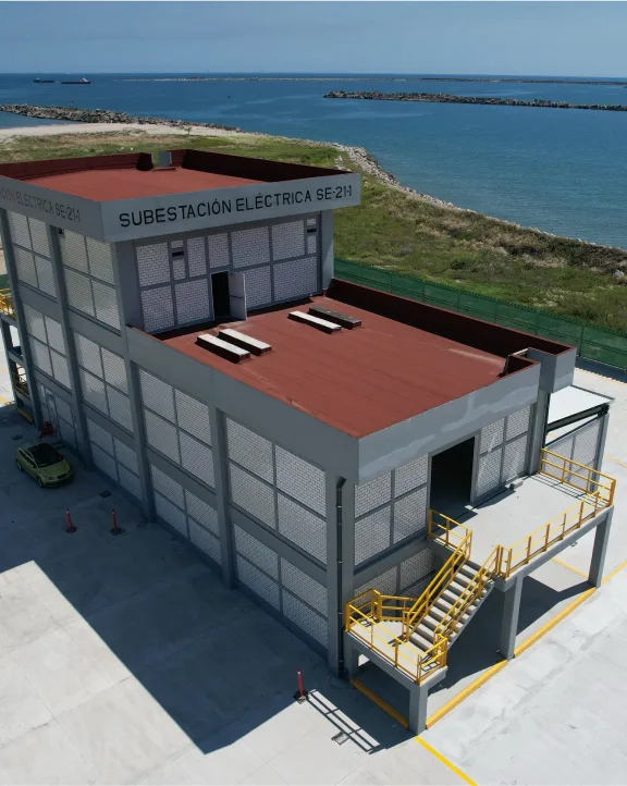 Two-story electrical substation building near a body of water.